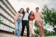 Group of friends walking together outside linking arms around shoulders