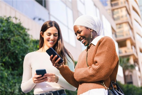 Two women smiling at mobile phones