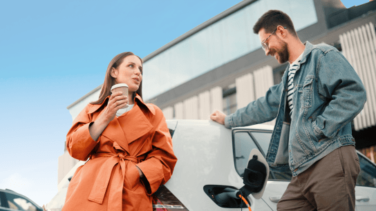 Man and woman drinking coffee next to EV 