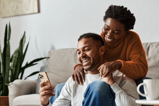 Man and woman smiling looking at smart phone