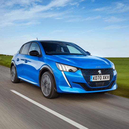 Peugeot e-208 in blue driving down country road 