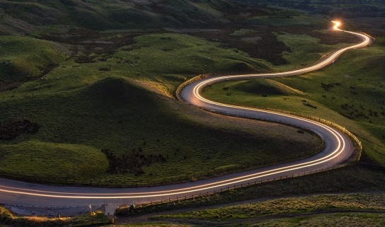 A winding road snakes into the distance through green hills