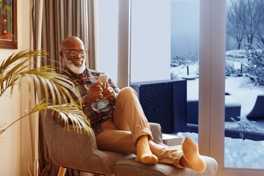 Man sitting inside cosy home with ashp unit outside