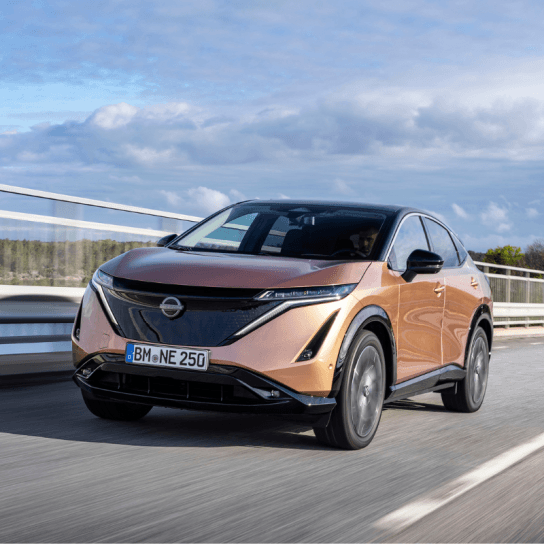 Nissan Ariya in gold driving down road 