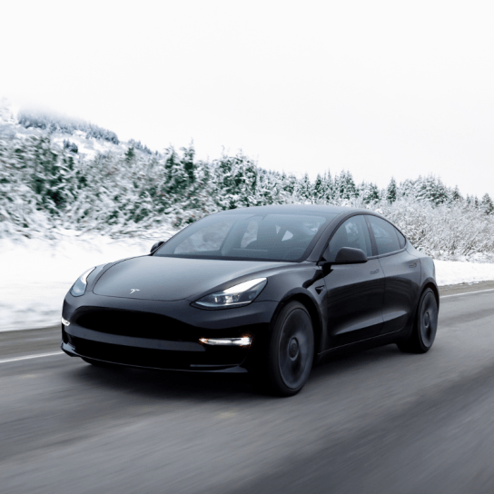 Tesla Model 3 in black driving on the road