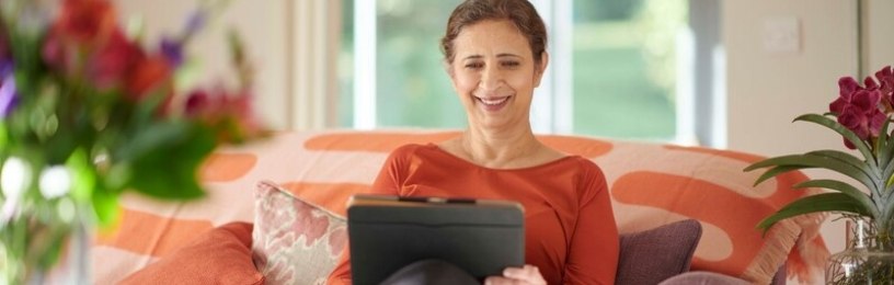 Woman sitting on sofa looking at iPad.